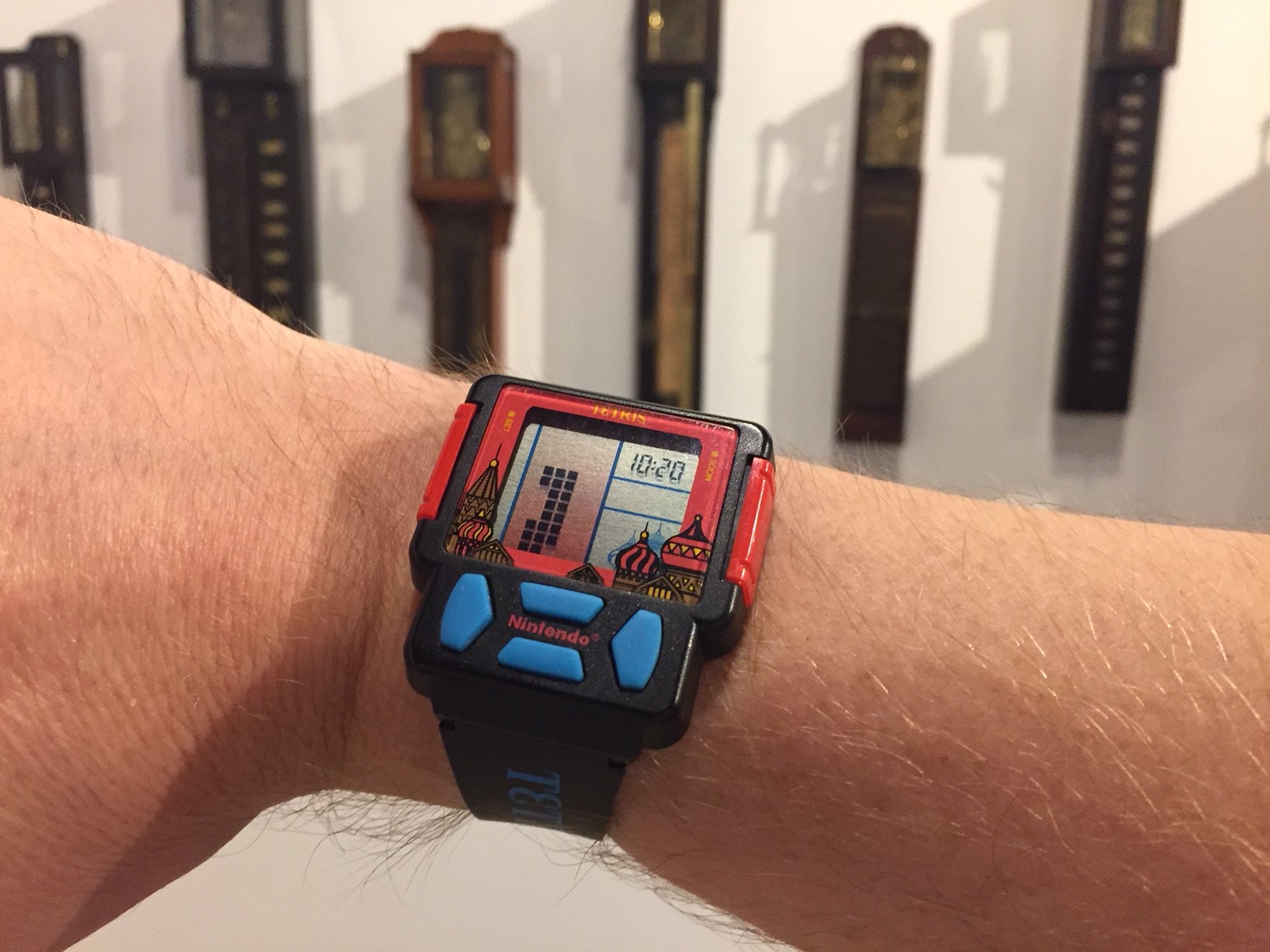 Tetris watch on man's wrist with Japanese shaku-dokei clock display in background at the National Watch & Clock Museum