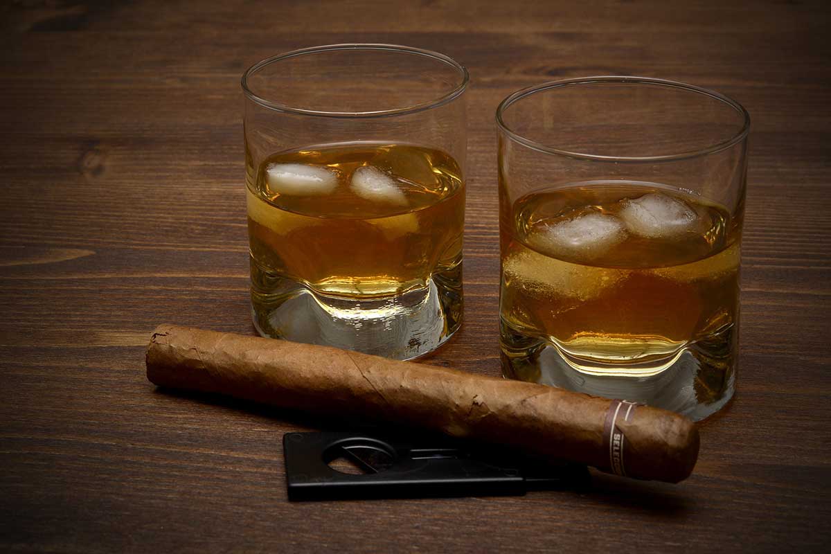 Photo of two whikey glasses and cigar with cigar cutter