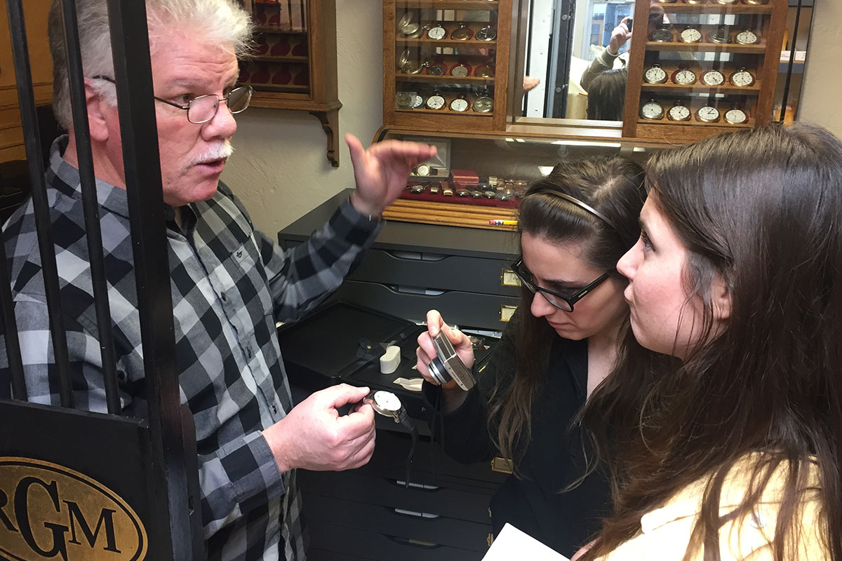 watchmaker roland murphey talking to two women in a vault full of wristwatches
