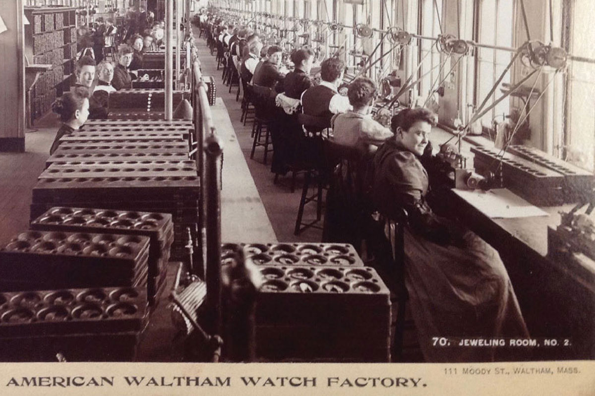 1890s photo of a factory line of women and men working in the jeweling room at the Waltham Watch Factory