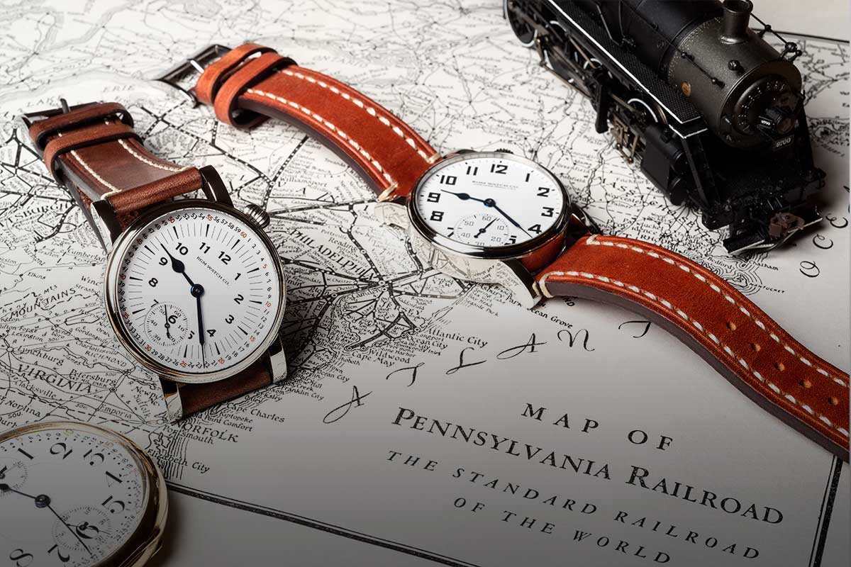 Two Model 222-RR wristwatches, a pocket watch, and a toy model of a steam locomotive, resting on a railroad map of Pennsylvania.